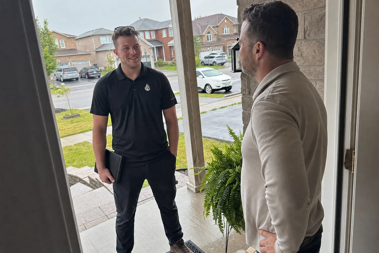 Reilly Morrison speaking with a homeowner at her front door on a rainy day - Platinum Gas Reilly Morrison speaking with a homeowner at her front door on a rainy day