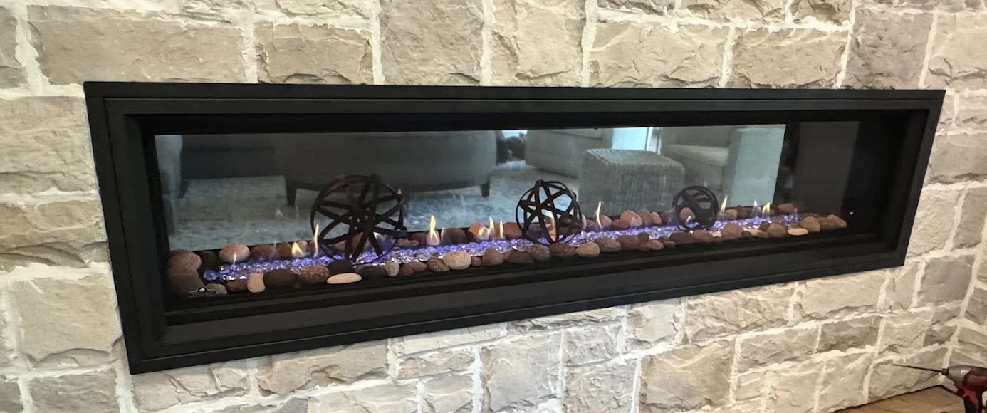 Finished linear gas fireplace in a stacked-stone wall by Platinum Gas