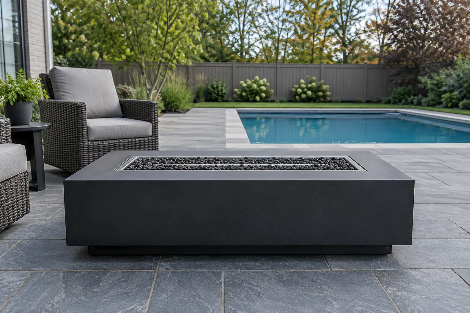 Low outdoor gas fire table and seating on a flat patio near a residential pool