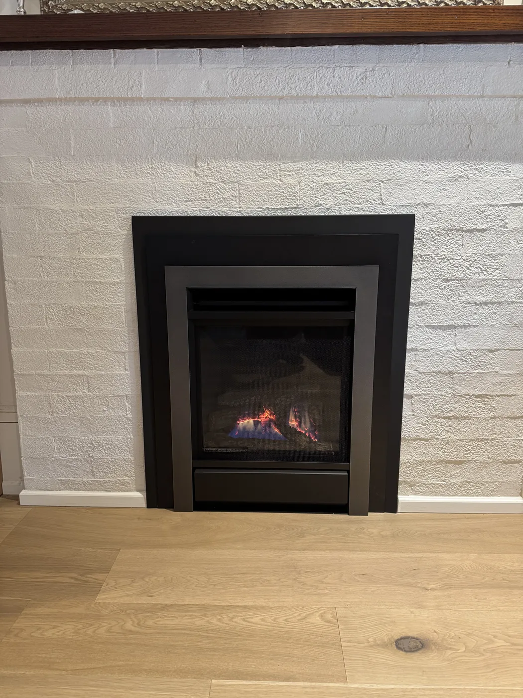 Gas insert in an existing painted brick fireplace, shared by Platinum Gas