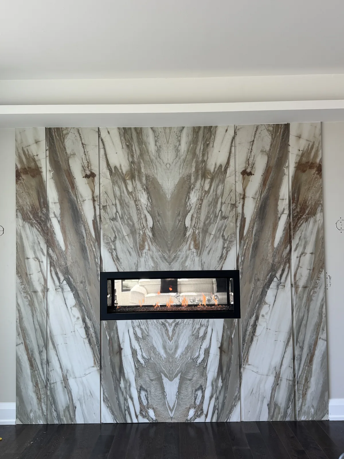 Linear gas fireplace set into a full-height veined stone feature wall, shared by Platinum Gas